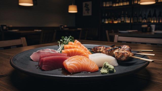 Assorted sashimi and robata skewers on a dark plate
