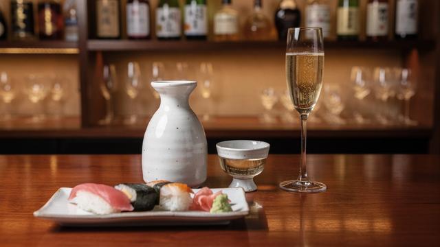 Sake and champagne glasses beside sushi plates